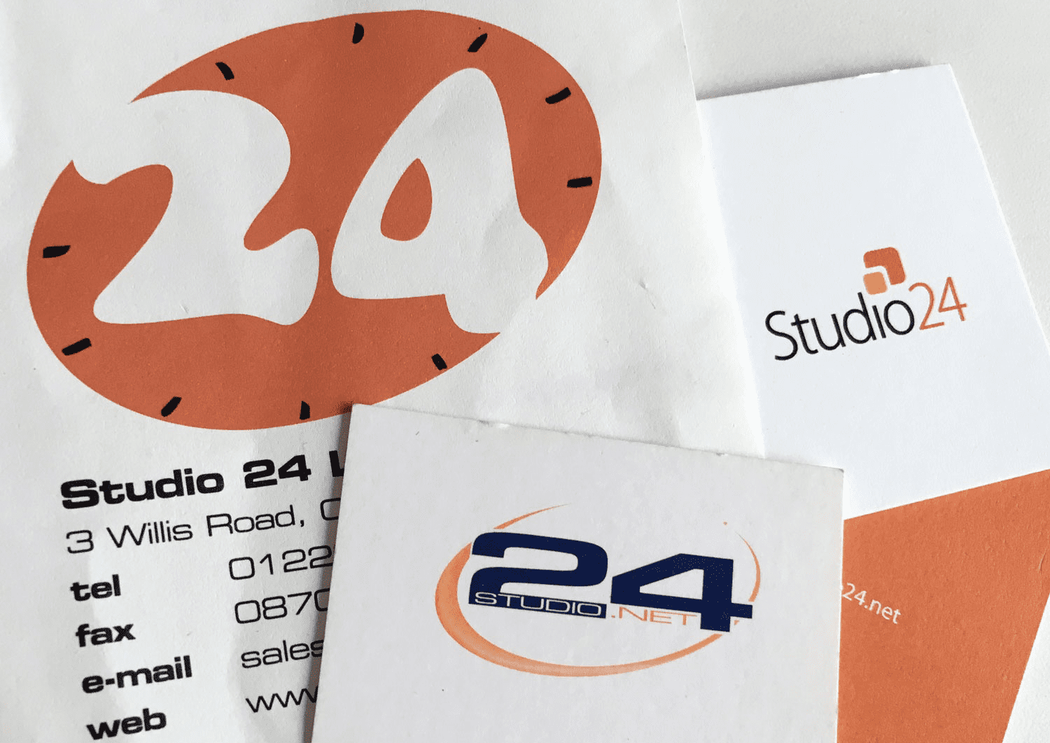 Three of studio 24's logos on letter headed paper. The first logo is a white '24' in an orange clock. The second logo is a dark blue '24' with an orange swoosh. The third logo has 2 orange squares like a thought bubble above the 'i' of studio.