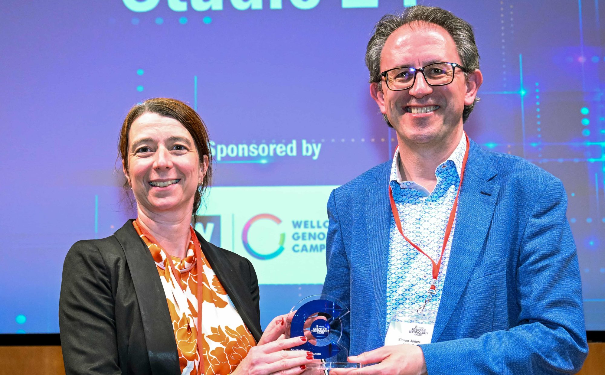 A woman is presenting a man with an award. They are both smiling broadly.